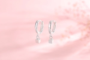Detailed close-up of s925 silver cube drop earrings on a soft pink romantic background