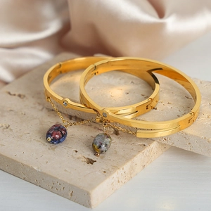 Elegant gold-plated bangle set with natural stone pendants and zircon on silk background