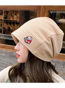 Close-up of beige knitted beanie featuring a cute heart cat patch on a female model