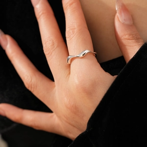 Macro shot of a minimalist silver wavy lava-style ring worn on the index finger