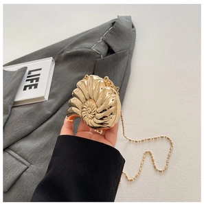 Detailansicht der goldenen Abendtasche in Schneckenform mit edler Perlenkette und Glanz