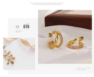 Detailed view of gold double-hoop earrings inlaid with white zircon on elegant fabric