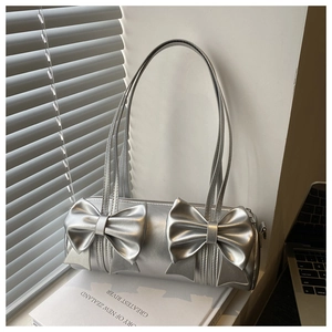 Detailed view of a silver metallic cylindrical handbag with stylish front bow accents