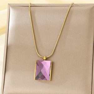 Detailed close-up of a purple faceted glass pendant on a gold snake chain necklace