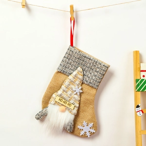 Close-up of linen Christmas stocking with gnome motif and HO HO HO wooden sign detail