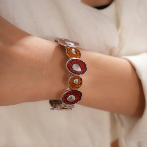 Détail d'un bracelet bohème élastique avec incrustation d'émail rouge et orange au poignet