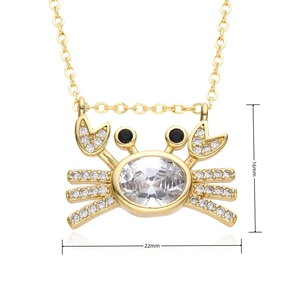Detail view of a gold-plated crab pendant with sparkling zircons and size dimensions