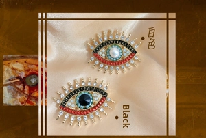 Macro detail of evil eye brooch with freshwater pearls and colorful crystals on gold base