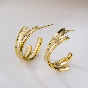 Detailed macro view of gold-plated C-shaped earrings with unique twisted layered design