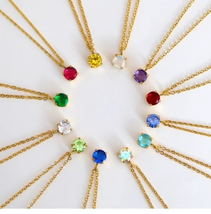 Detailed overhead view of twelve different colored zircon birthstone pendants on gold chains