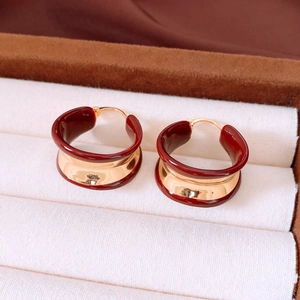 Close-up of 18k gold plated round hoop earrings with burgundy enamel in a jewelry box