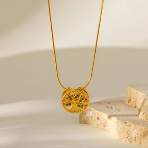 Detail of gold snake chain necklace featuring a tree of life pendant with blue zircon