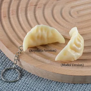 Realistic PVC dumpling keychains and food models on a minimalist light wood tray