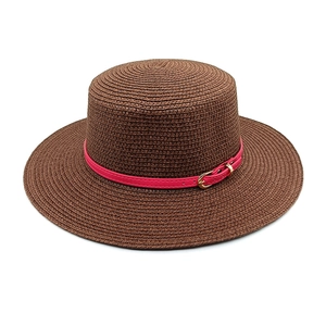 Detailed texture of brown straw boater hat with fuchsia faux leather belt and gold buckle