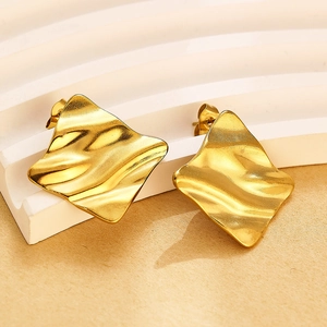Vue détaillée de boucles d'oreilles dorées ondulées sur escaliers géométriques