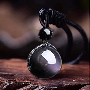 Polished 16mm black obsidian pendant necklace on woven cord over a rustic wood surface