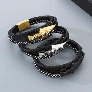 Dettaglio di bracciali multistrato in pelle con ciondoli a freccia e chiusura magnetica
