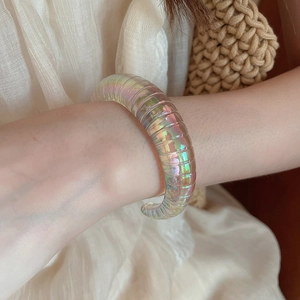 Macro view of iridescent acrylic cuff bracelet with spiral texture and aurora finish