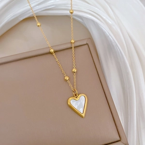 Macro detail of a gold heart pendant with white mother-of-pearl inlay on silk background