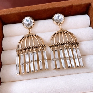 Dettaglio di orecchini vintage in oro con nappe di zircone in un portagioie marrone