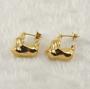 Macro shot of gold plated stainless steel earrings with irregular molten metal texture