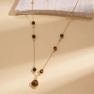 Detail view of retro gold flower necklace with tiger eye beads on natural stone background