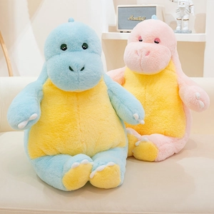 Detail view of plush dinosaur pillow in blue and pink on a cozy living room sofa