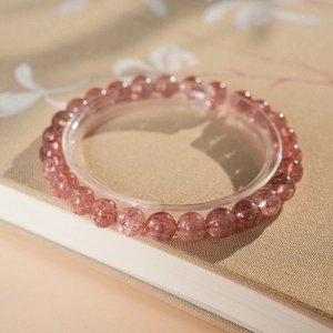 Macro view of strawberry quartz bead bracelet on elegant vintage floral paper background