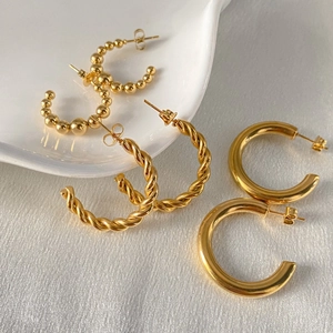Detail of three pairs of gold-plated stainless steel hoop earrings in various designs