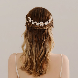 Detail of white ceramic flowers on gold wire bridal hair comb worn on braided hair