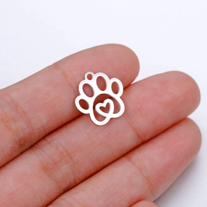 Polished stainless steel cat paw pendant with heart cutout held to show small size