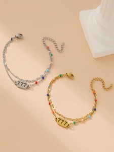 Dettaglio del bracciale a doppia catena dorata con perline colorate e placchetta numero 777