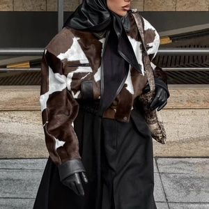 Detail of faux fur cow print jacket with leather patchwork in a street style design