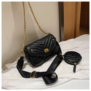 Detail of black quilted crossbody bag with gold chain strap and extra round coin pouch