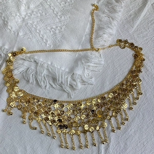 Detailed view of bohemian gold waist chain with intricate coin tassels and bells.