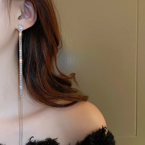 Elegant silver tassel earrings with zircon stones worn by a model on a clean backdrop