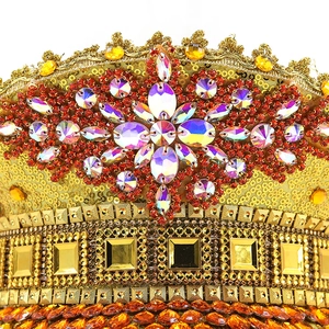 Macro view of gold sequined festive crown with colorful crystals and red rhinestones