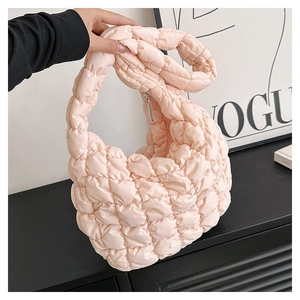 Detail of light pink quilted cloud bag featuring soft padded fabric and knotted top handle