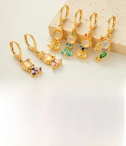 Macro detail of gold-plated fish tail princess earrings with sparkling colorful zircons