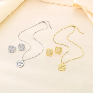 Detailed view of square 18K gold and silver plated jewelry sets on cream fabric