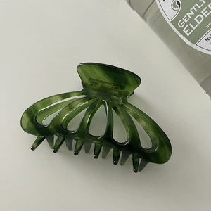 Close-up of a large dark green resin hair claw clip with elegant hollow curved ribs
