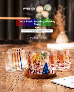 Three hand-painted spinning whiskey glasses with colorful patterns on a wooden tabletop