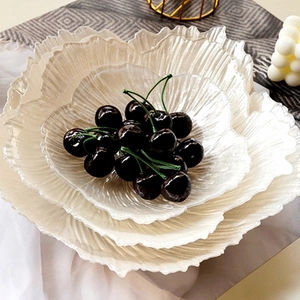 Macro shot of white ruffled glass plates with pearl finish and fresh dark cherries