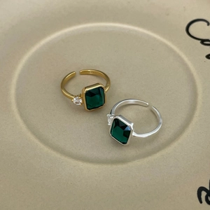 Detailed top view of gold and silver minimalist rings with emerald cut green gemstones