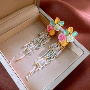 Detail of vintage floral tassel earrings with pink resin roses and golden metal chains