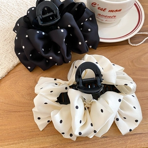 Detailed view of large polka dot bow hair claw clips on a warm wooden background