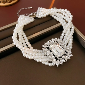 Macro shot of multi-layered pearl choker necklace with ornate crystal brooch detail