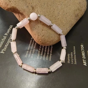 Detailed close-up of a pink quartz crystal bead bracelet with silver spacers on a raw stone