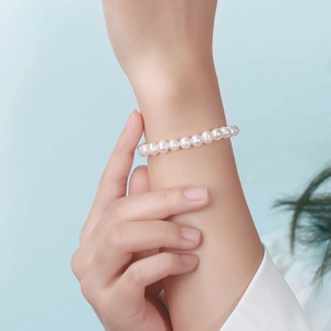 Gros plan d'un bracelet en perles d'eau douce au poignet sur un fond bleu élégant