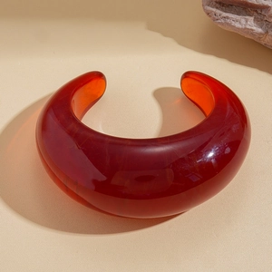 Macro shot of bold deep red resin open bangle with a polished smooth finish and thick texture